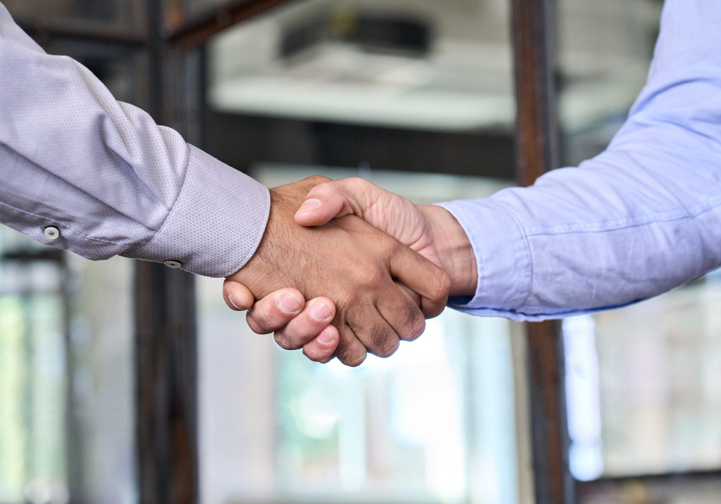 Two businessmen shake hands with business handshake at office meeting. Manager and client or partners trust and acquisition partnership, trade agreement, help and cooperation, leadership concept.